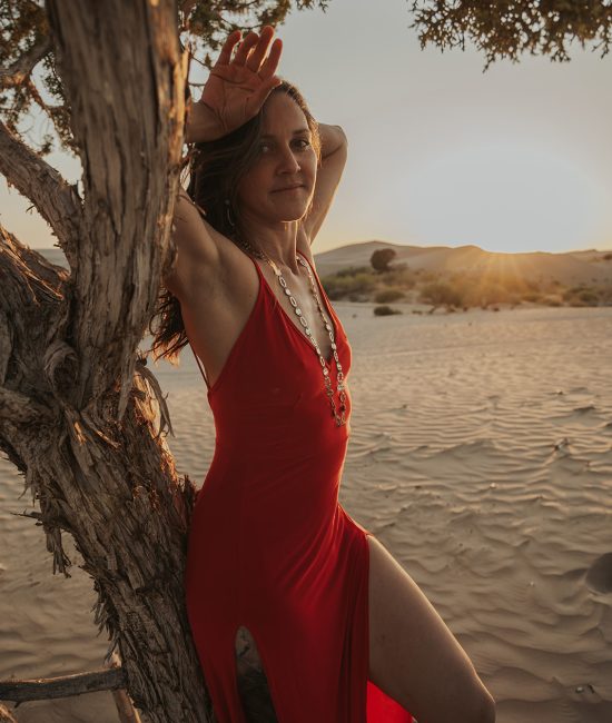 a woman in a red dress in the sand dunes