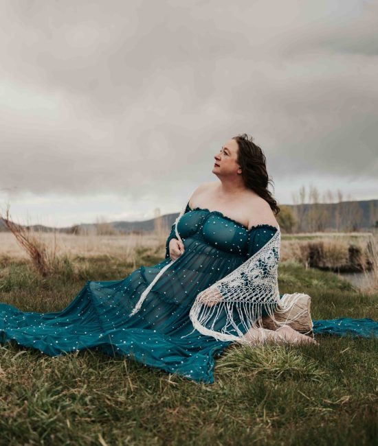 A woman sitting in a field gazing up at the sky
